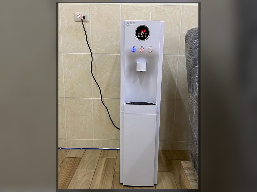 白色智慧三溫機落地式靠在磁磚牆邊，電線接到上方插座