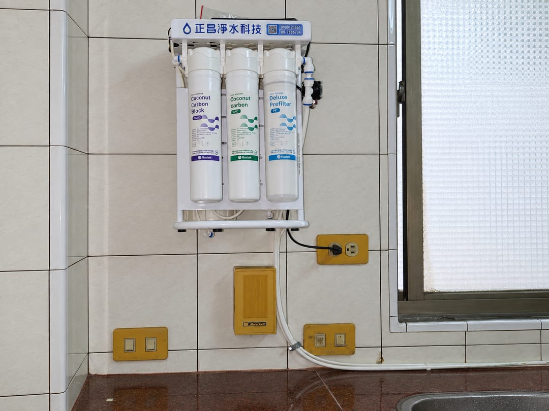 壁掛在磁磚牆上的直輸型 RO 主機，下方是插座