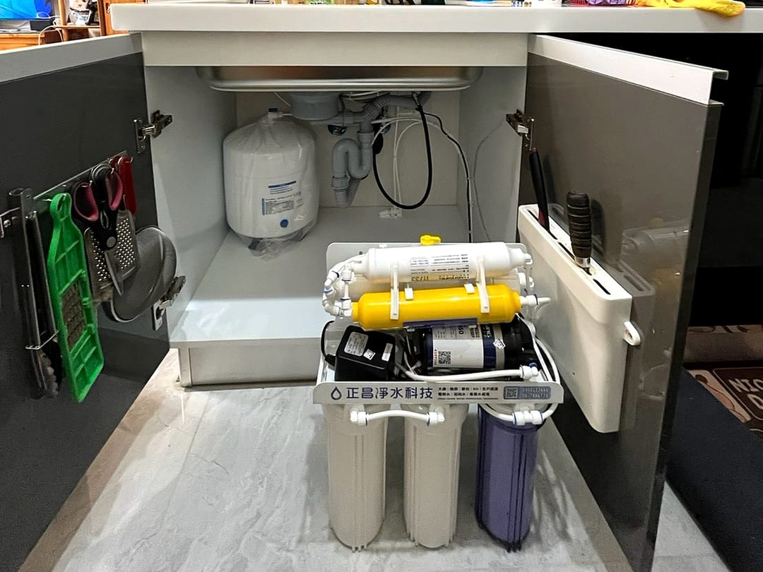 抽屜式廚櫃裡的有壓力桶 RO 機，壓力桶靠牆放、主機在前