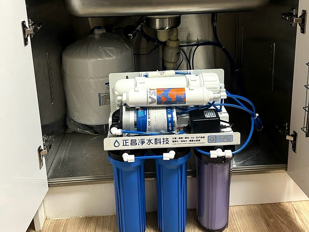 木紋廚櫃裡的有壓力桶 RO 機，藍色濾瓶與紫色濾瓶並排